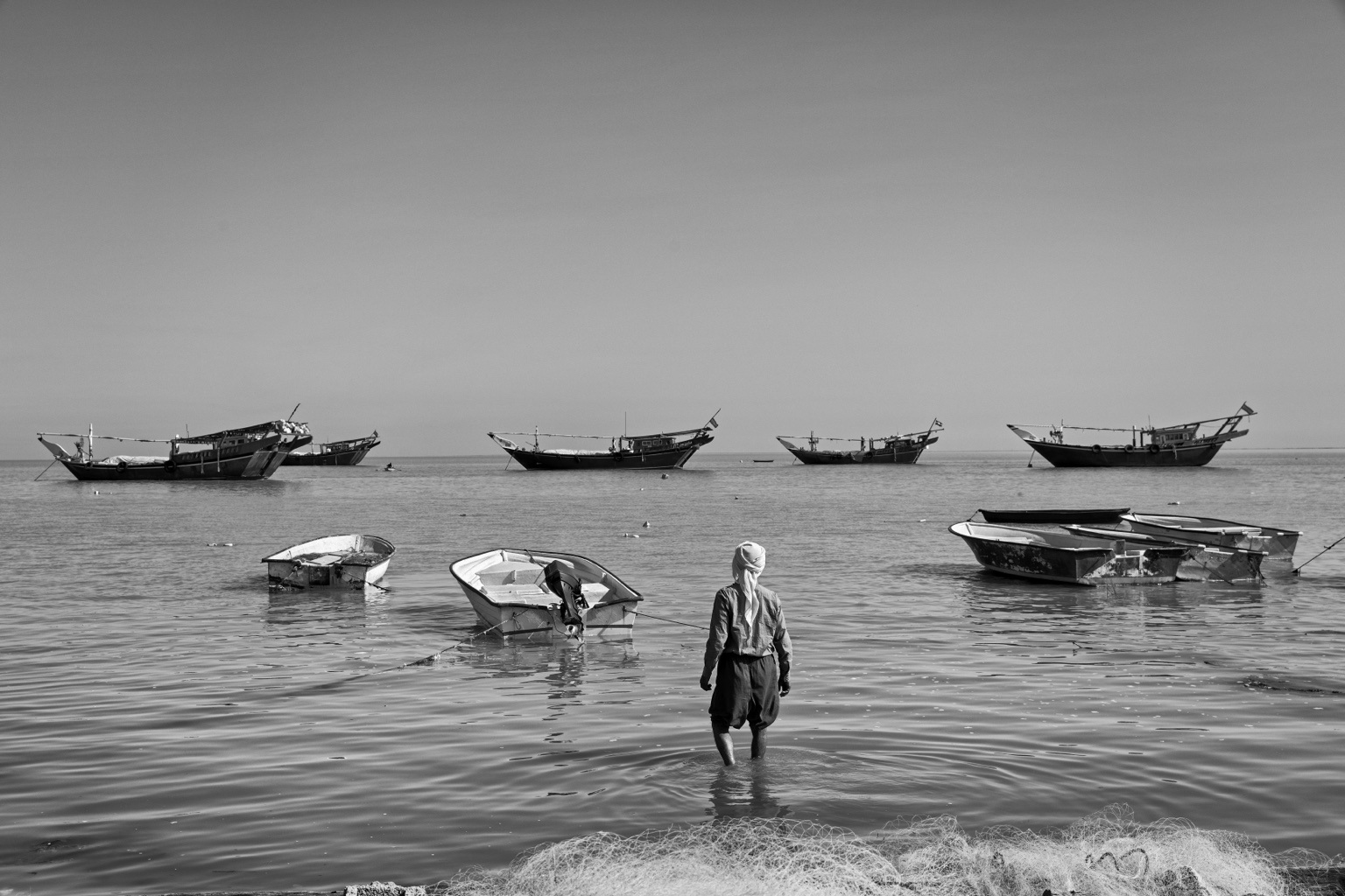 A fisherman carrying his catch through shallow coastal water